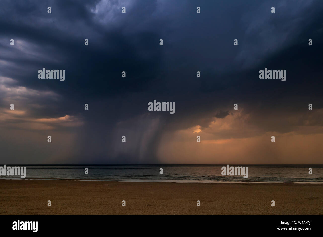 Thunderstorm showing dark rain clouds and cloudburst / deluge over the sea during heatwave / heat wave in summer Stock Photo