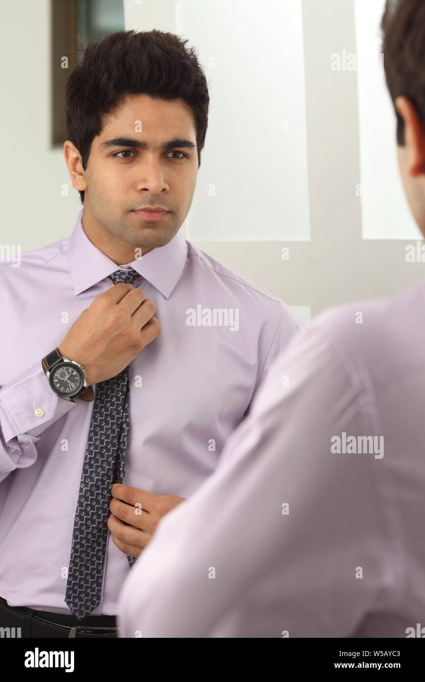 Businessman adjusting tie in mirror Stock Photo Alamy