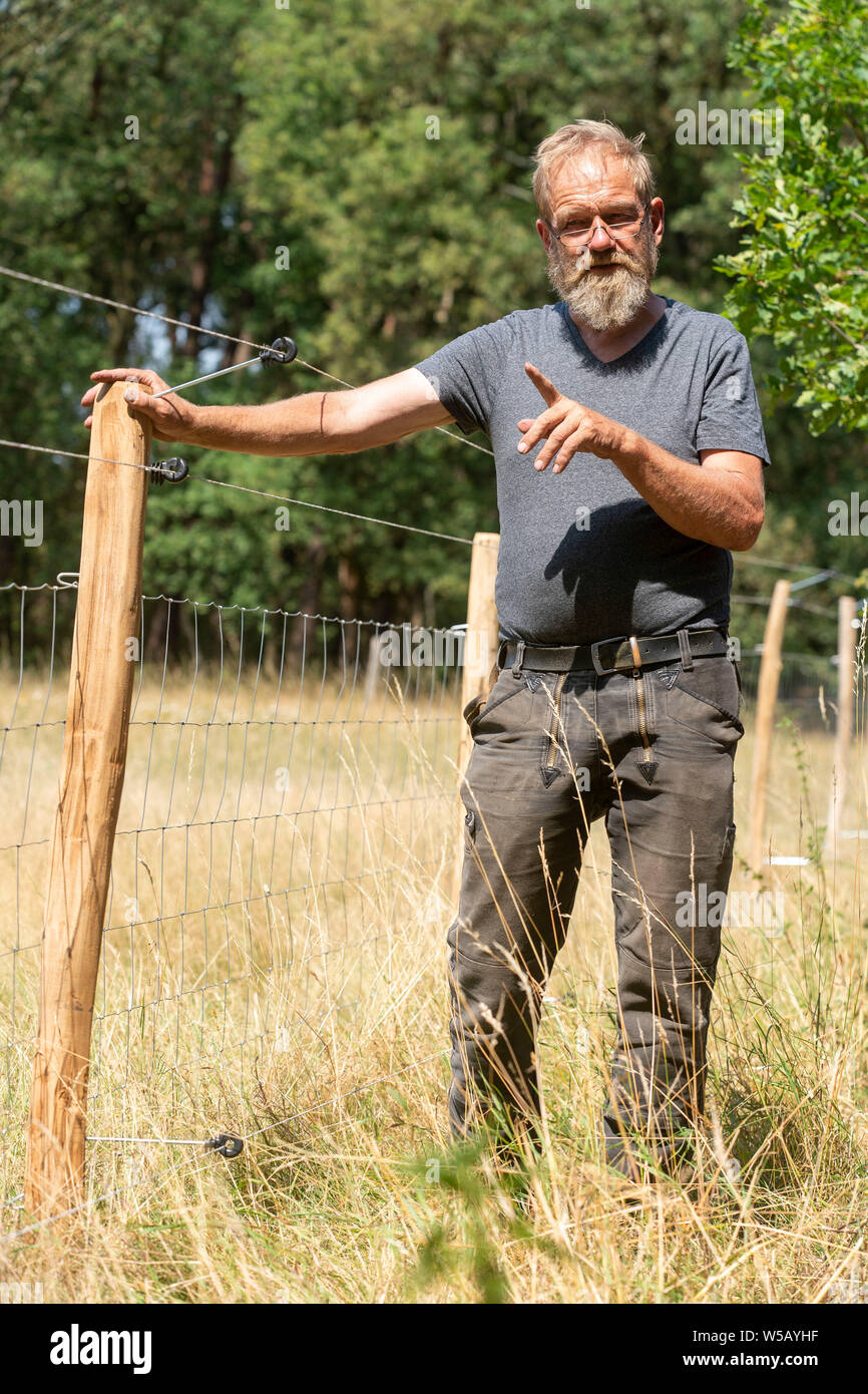 Hamminkeln Dingden, Germany. 27th July, 2019. Schäfer Achim Koop presents a wire fence built by him, which is partly electrically secured. The fence stands next to its pasture in the Dingden Heath, where three years ago some of its animals were torn by a wolf. The Lower Rhine region is one of three areas in North Rhine-Westphalia in which a wolf has settled. Credit: Arnulf Stoffel/dpa/Alamy Live News Stock Photo