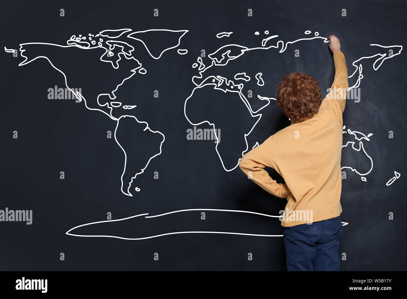 Child student drawing map of Earth on chalkboard in classroom. Environmental protection concept Stock Photo