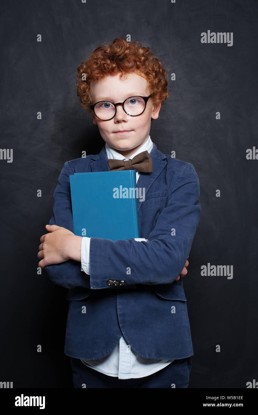 Kid and book on blackboard background. Cute child boy wearing glasses Stock Photo