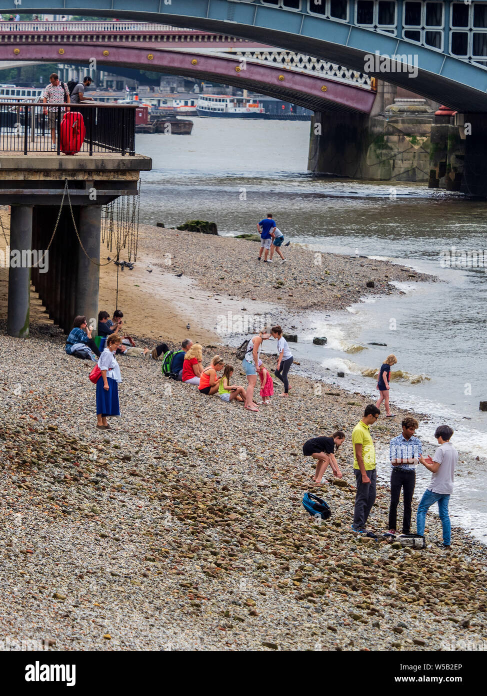 London Thames Beach - people relax on the banks of the River Thames at low tide in Central London during hot weather Stock Photo