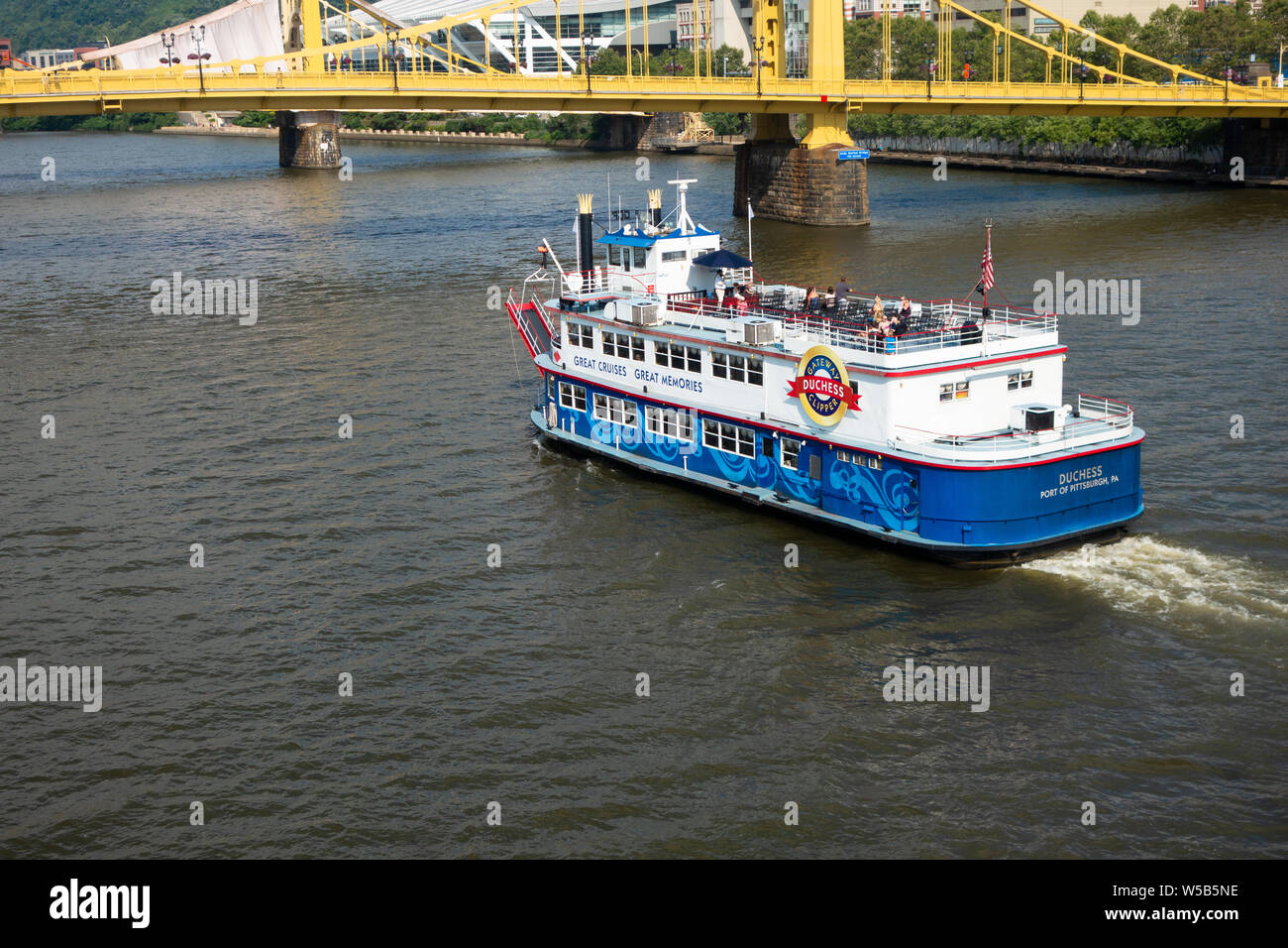 The Duchess, a river paddleboat that is part of the Gateway Clipper Fleet, passes near the Pittsburgh city skyline and the Andy Warhol Bridge. Stock Photo