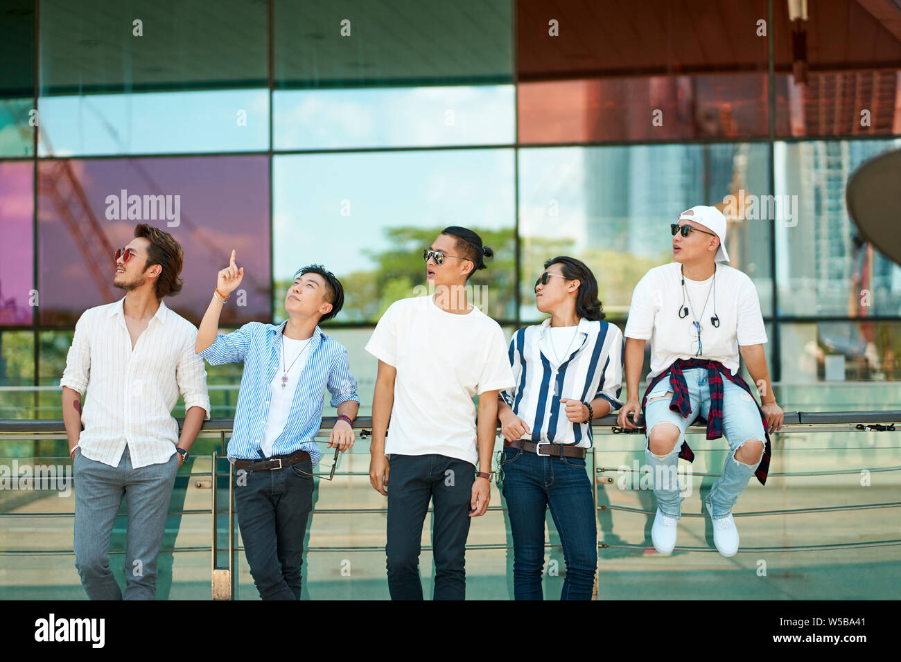 a group of five young asian adults hanging out together on street Stock Photo
