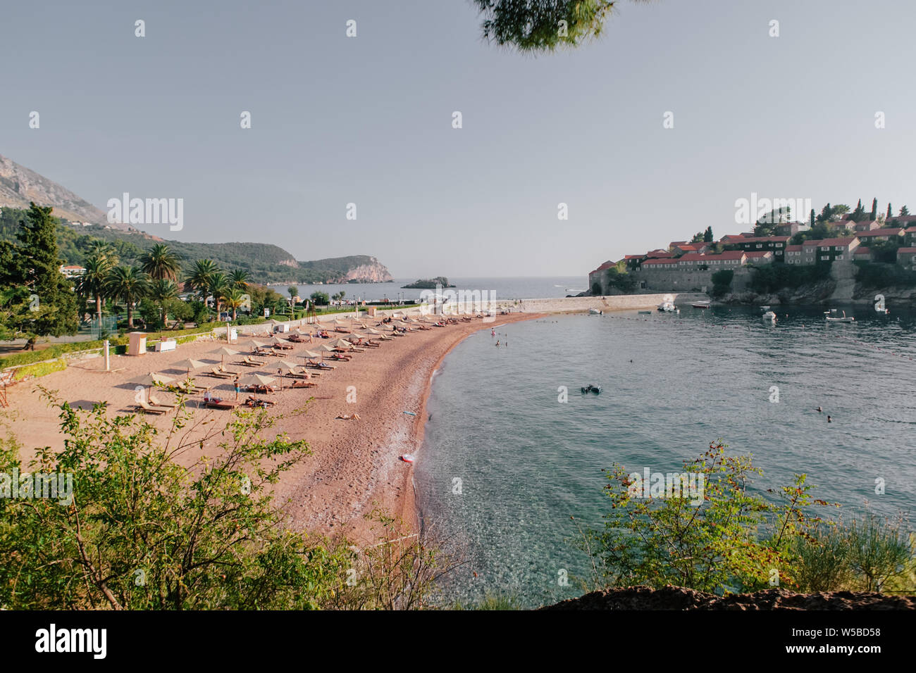People sunbathe and swim on the beach of the resort Sveti Stefan in Montenegro Stock Photo