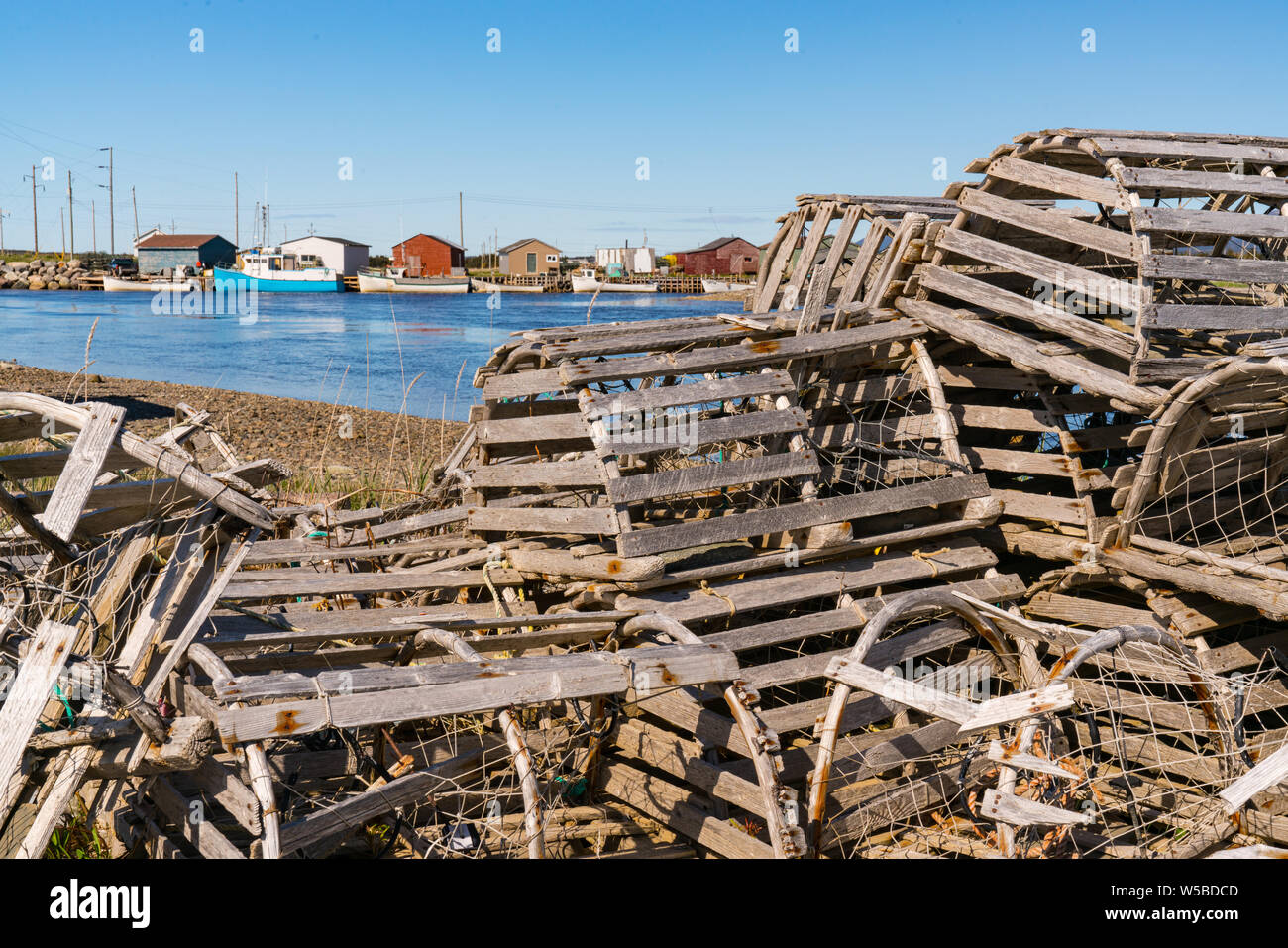 Old wooden lobster traps and fishing boats in a fishing village in Newfoundland, Canada Stock Photo