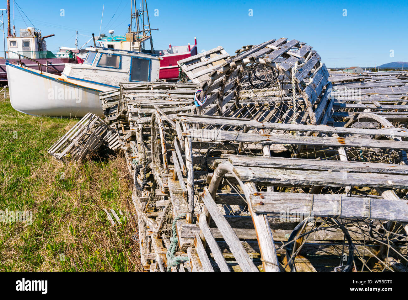 Old wooden lobster traps and fishing boats in Newfoundland, Canada Stock Photo