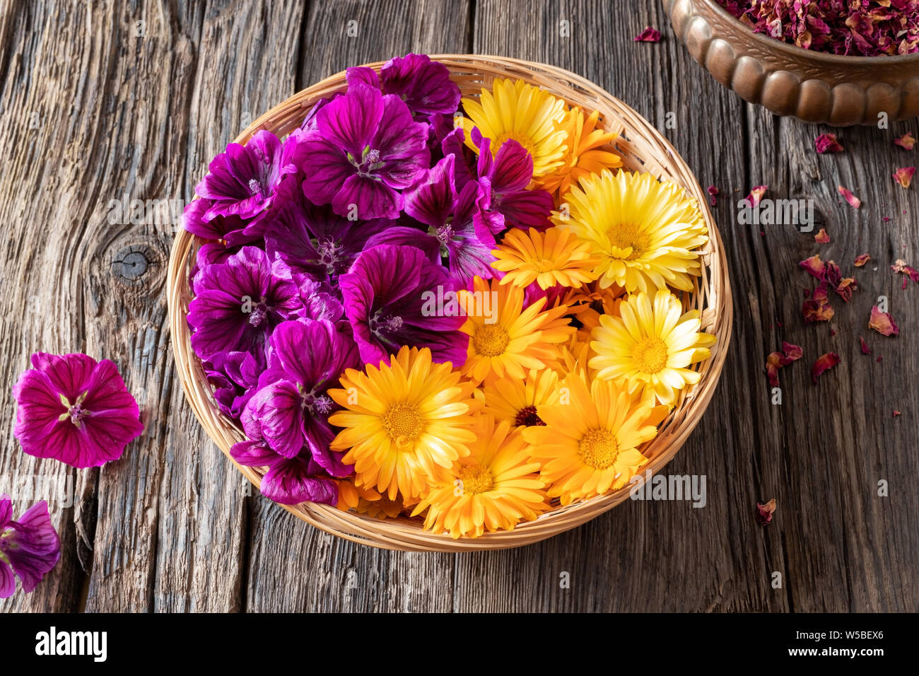 Fresh calendula and malva sylvestris mauritiana flowers in a basket Stock Photo