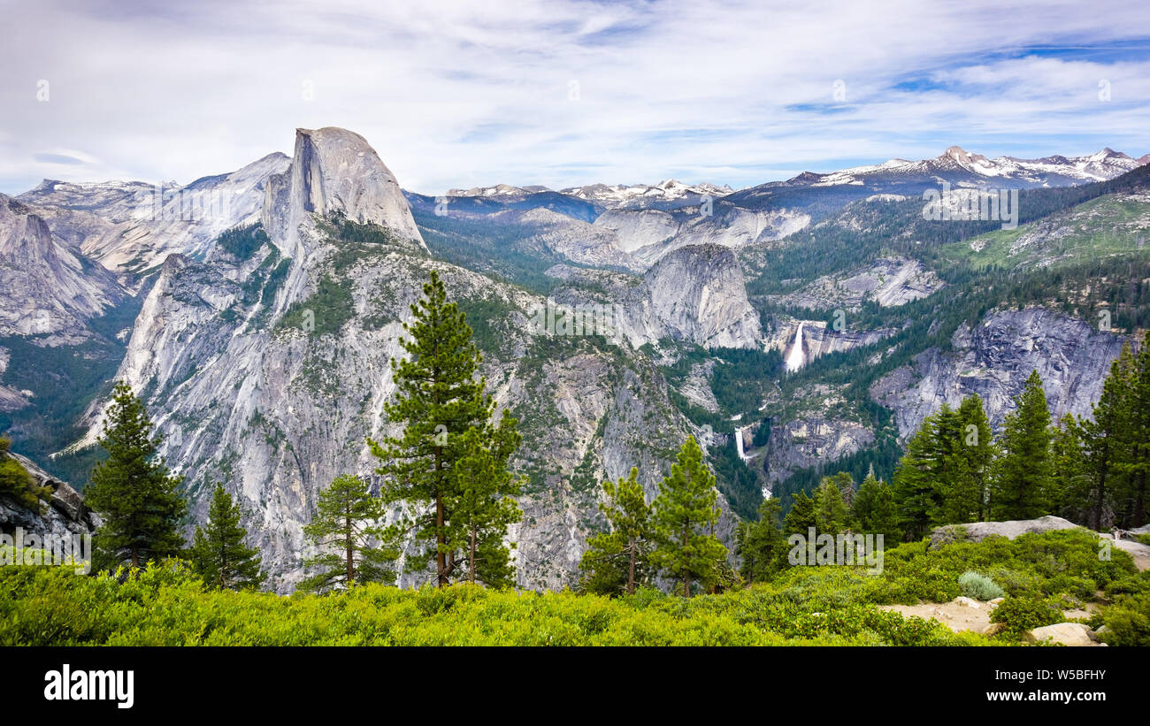 View towards Half Dome; Vernal Fall, Nevada Fall and Liberty Dome visible on the right; snow capped mountains in the background; Yosemite National Par Stock Photo