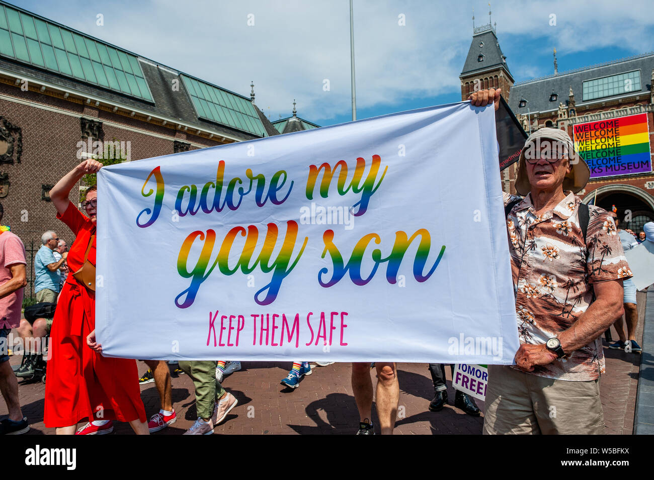 A banner that says, I adore my gay son, during the Pride Walk.Because of the Stonewall 50th anniversary, the Pride Walk theme this year is ‘Remember the past, create the future’. The Pride Walk is a demonstrative and activist walk from the Homomonument to the Vondel Park. This is the 'counterpart' of the world-famous boat parade that takes place a week later on August 5th. Thousands of people participated by carrying the flags of the countries where homosexuality is in the Penal Code. Stock Photo