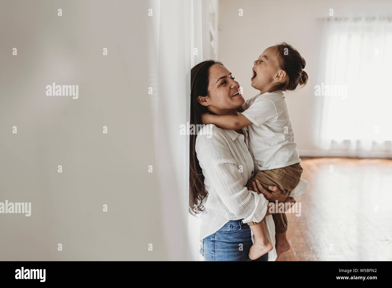 Side view of young mother holding toddler boy in embrace in studio Stock Photo