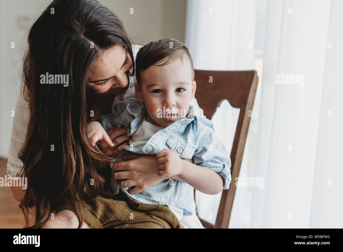 Close up of young preschool age boy being embraced by mother in studio Stock Photo