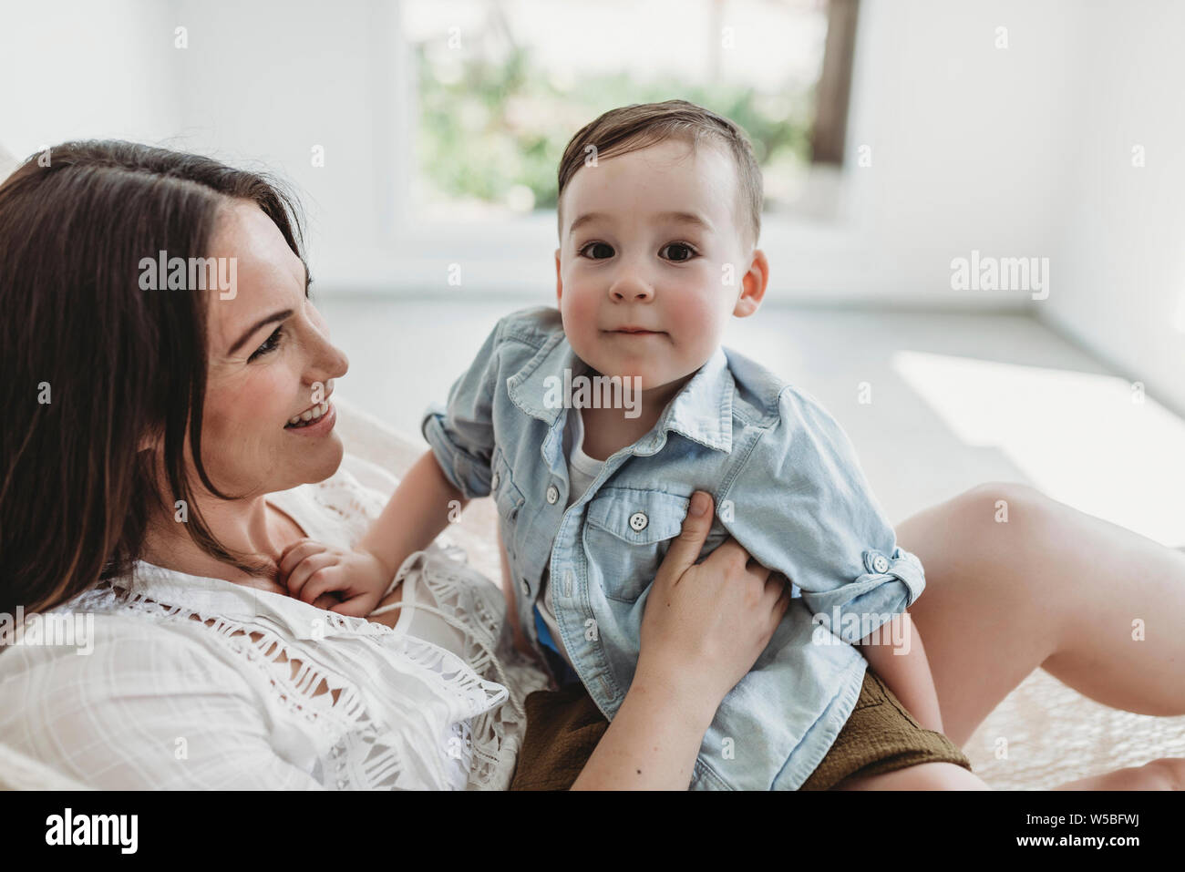 Mother and young son swinging in hammock in natural light studio Stock Photo