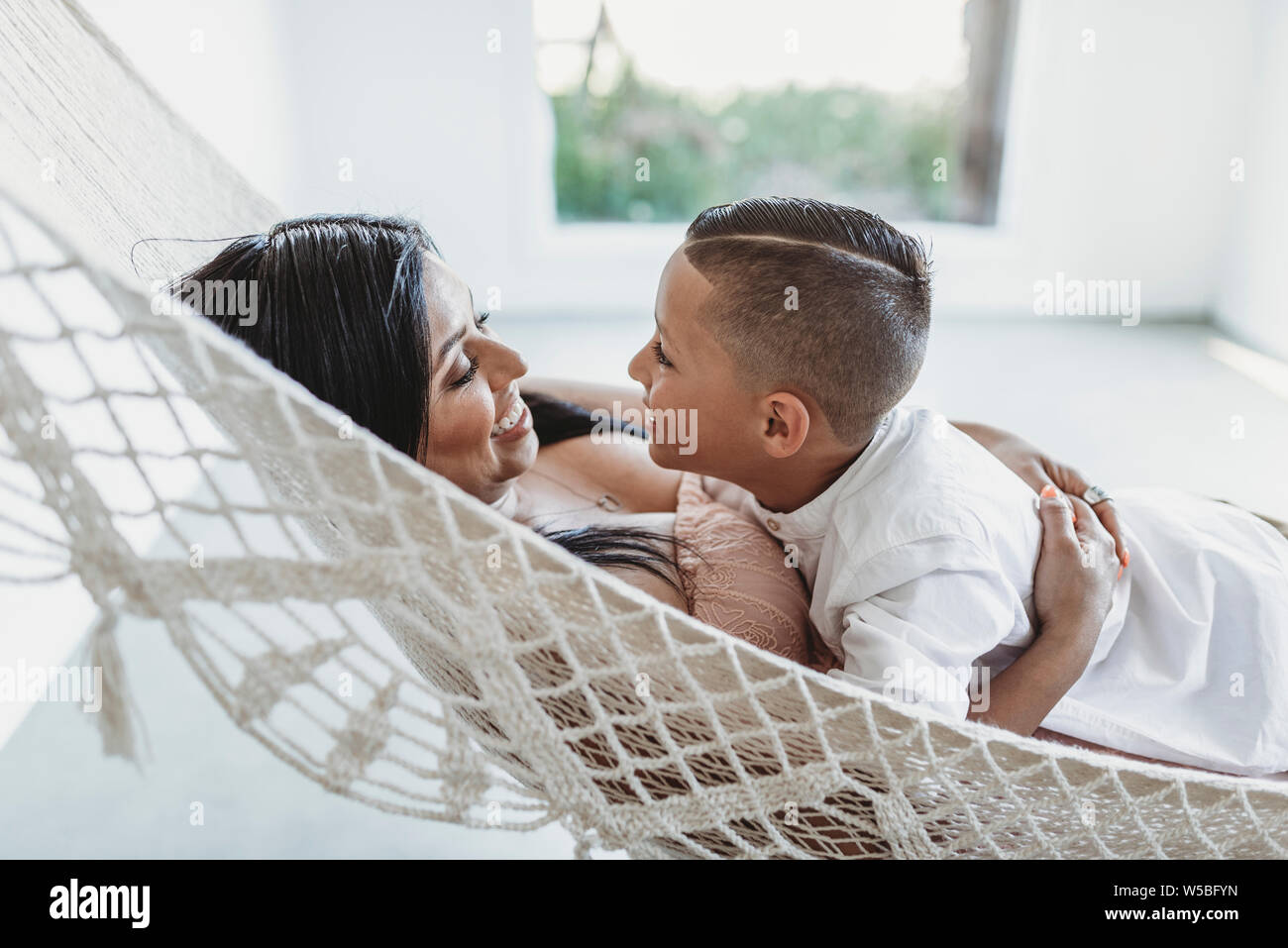 Mother and young son looking at each other while laying in hammock Stock Photo