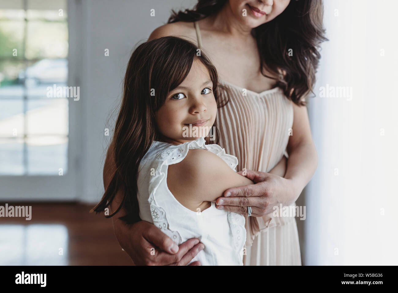 Mid level view of school aged girl being hugged by mother Stock Photo