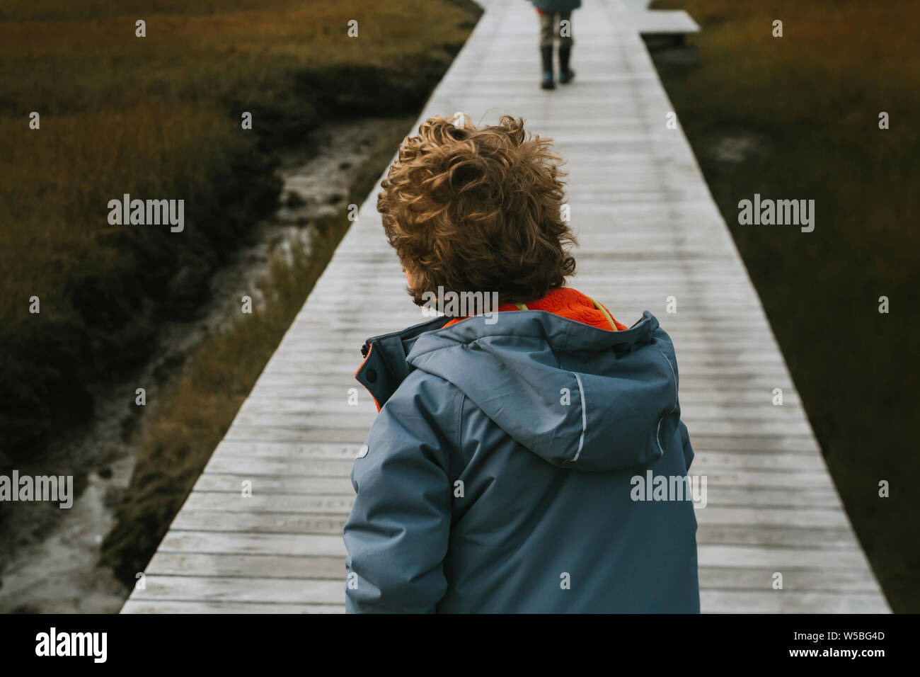 Rear view of child with curly hair on boardwalk Stock Photo