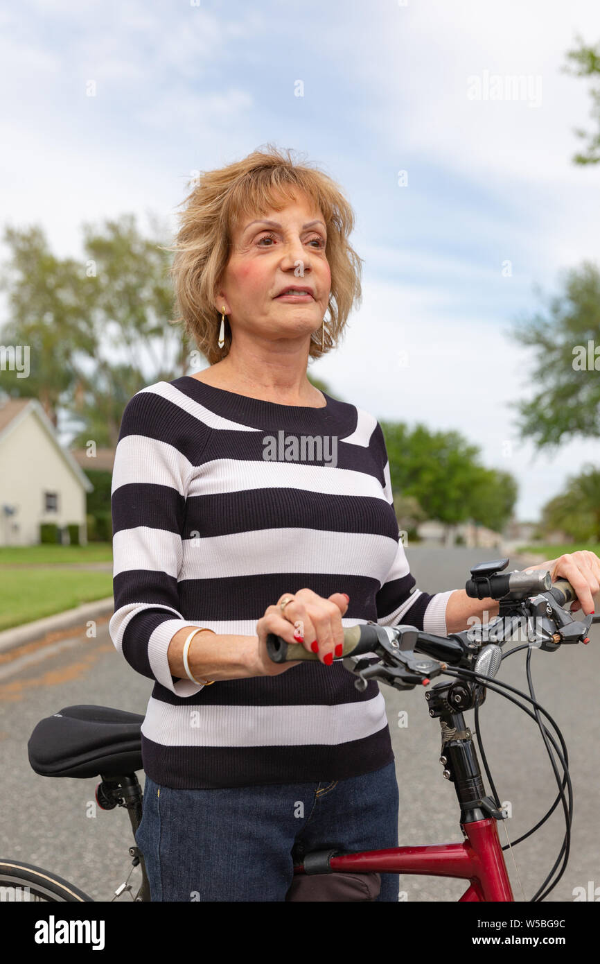 Mature woman in her seventies enjoying a day outside on her bike. Stock Photo