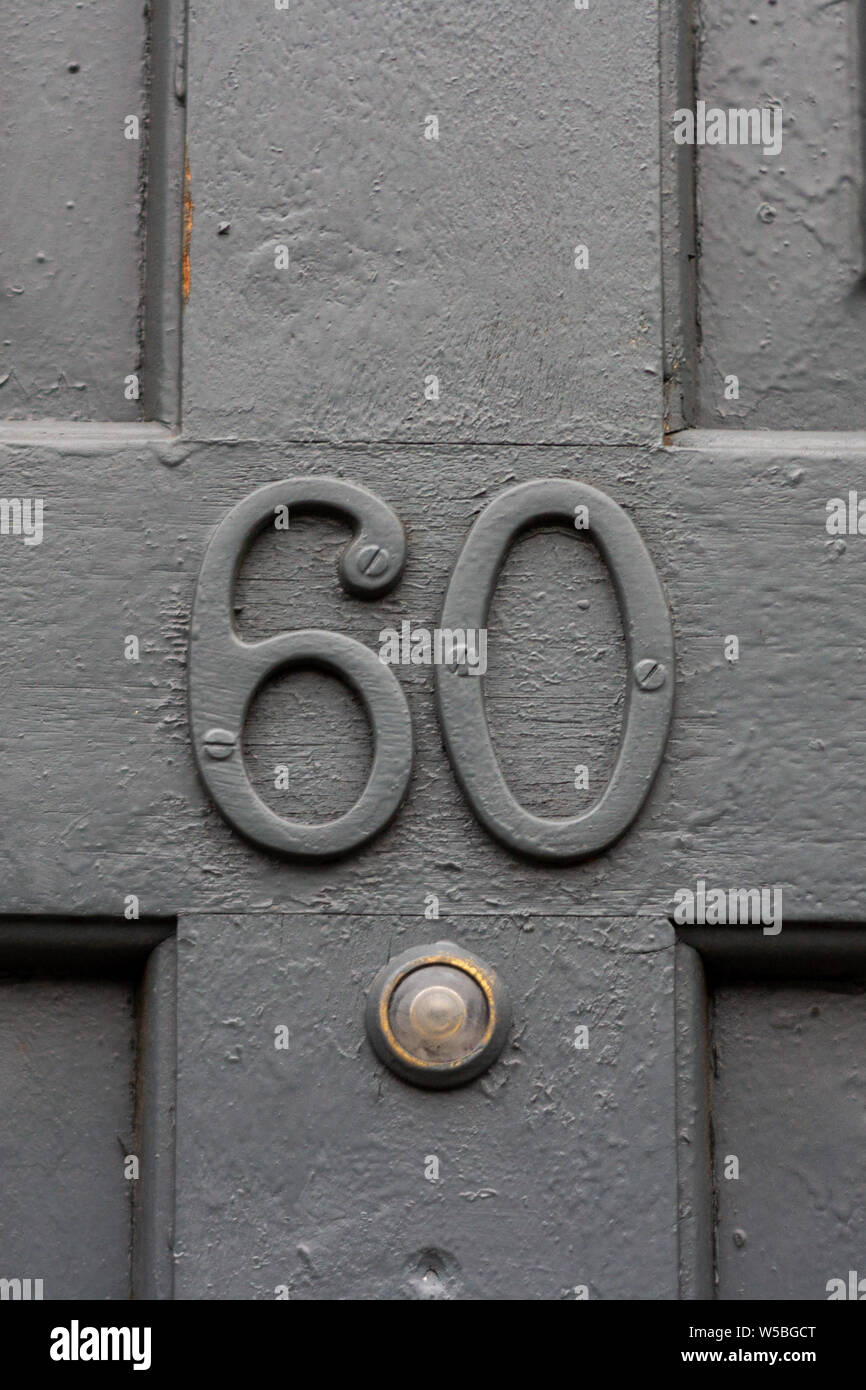House number 60 with the sixty painted in grey on a grey wooden front door Stock Photo