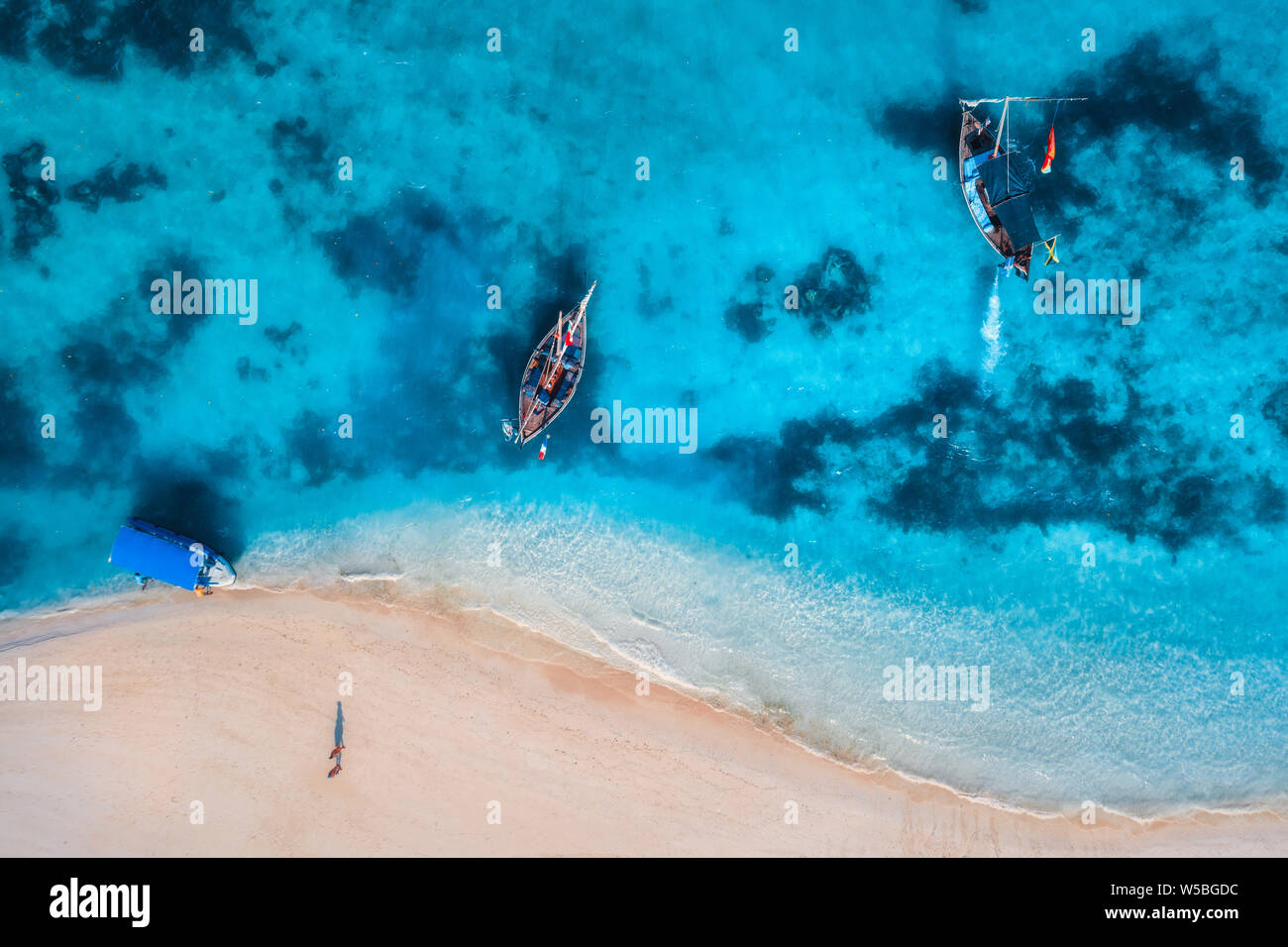 Aerial view of the fishing boats in clear azure water at sunrise in ...