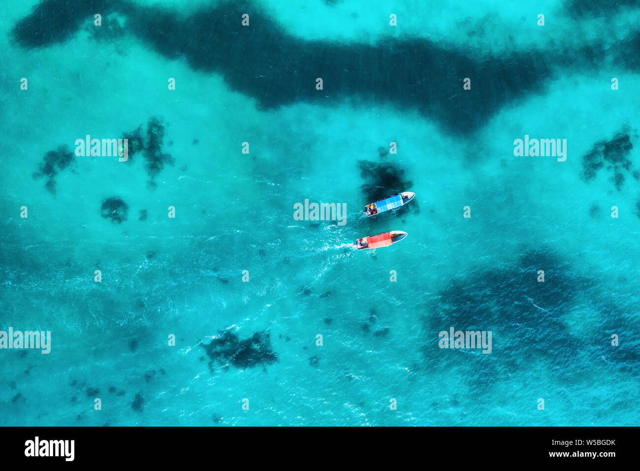 Aerial view of the fishing boats in transparent blue water at sunset in ...