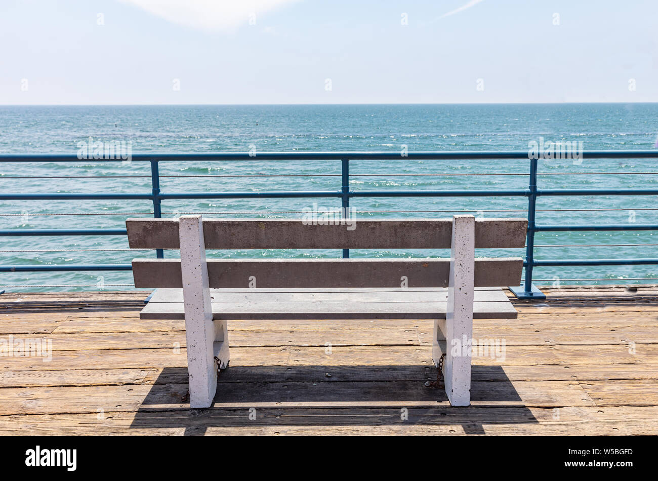 Empty bench with sea view on wooden deck, blue sky and sea background, Santa Monica pier, California Stock Photo