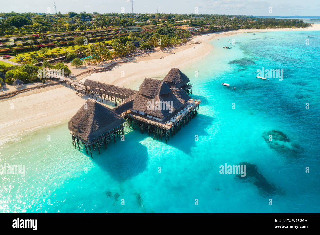 Aerial view of beautiful hotel on the water in ocean at sunset in summer. Zanzibar, Africa. Top view. Landscape with wooden hotel on the sea, azure wa Stock Photo