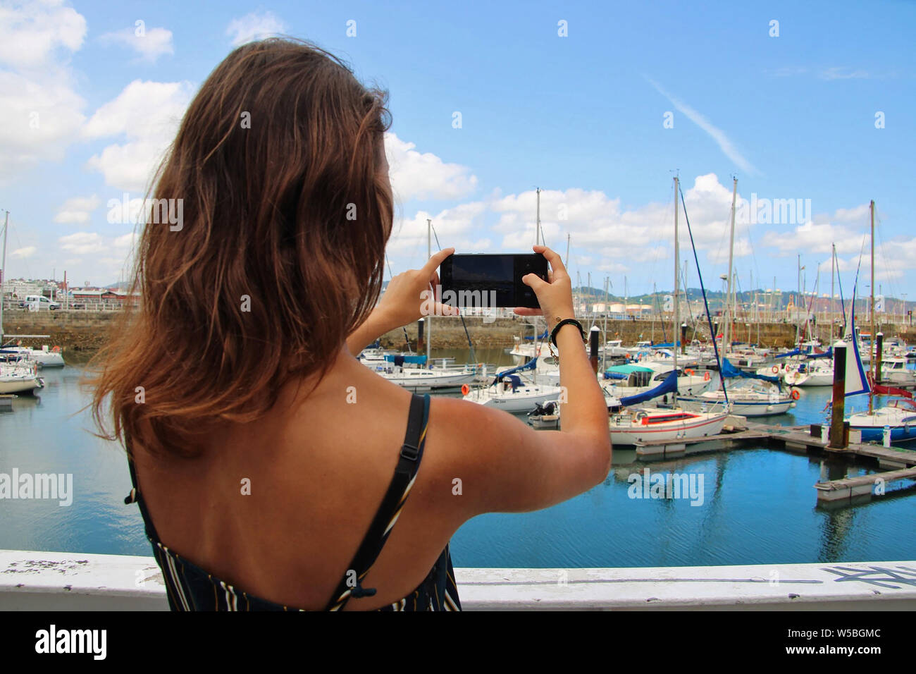 Young woman taking a picture of a port. Stock Photo