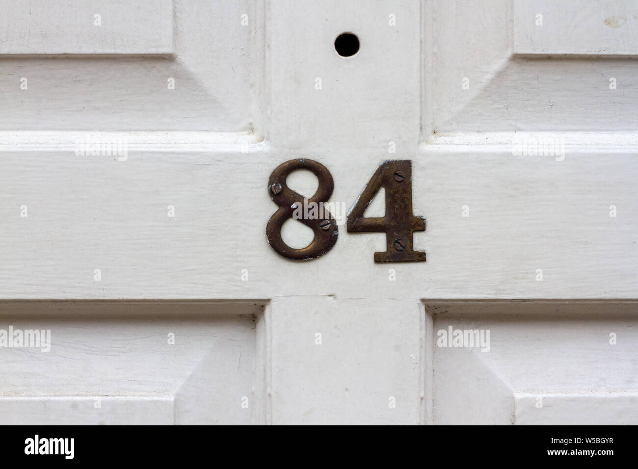 House number 84 on a white wooden front door Stock Photo