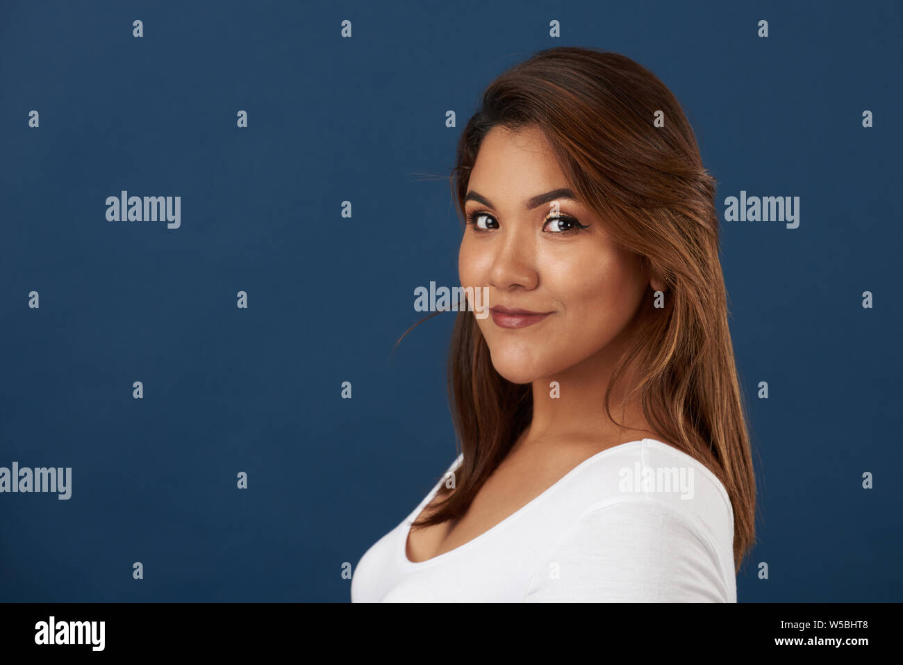 Pretty young latina girl portrait with copy space on blue background Stock Photo