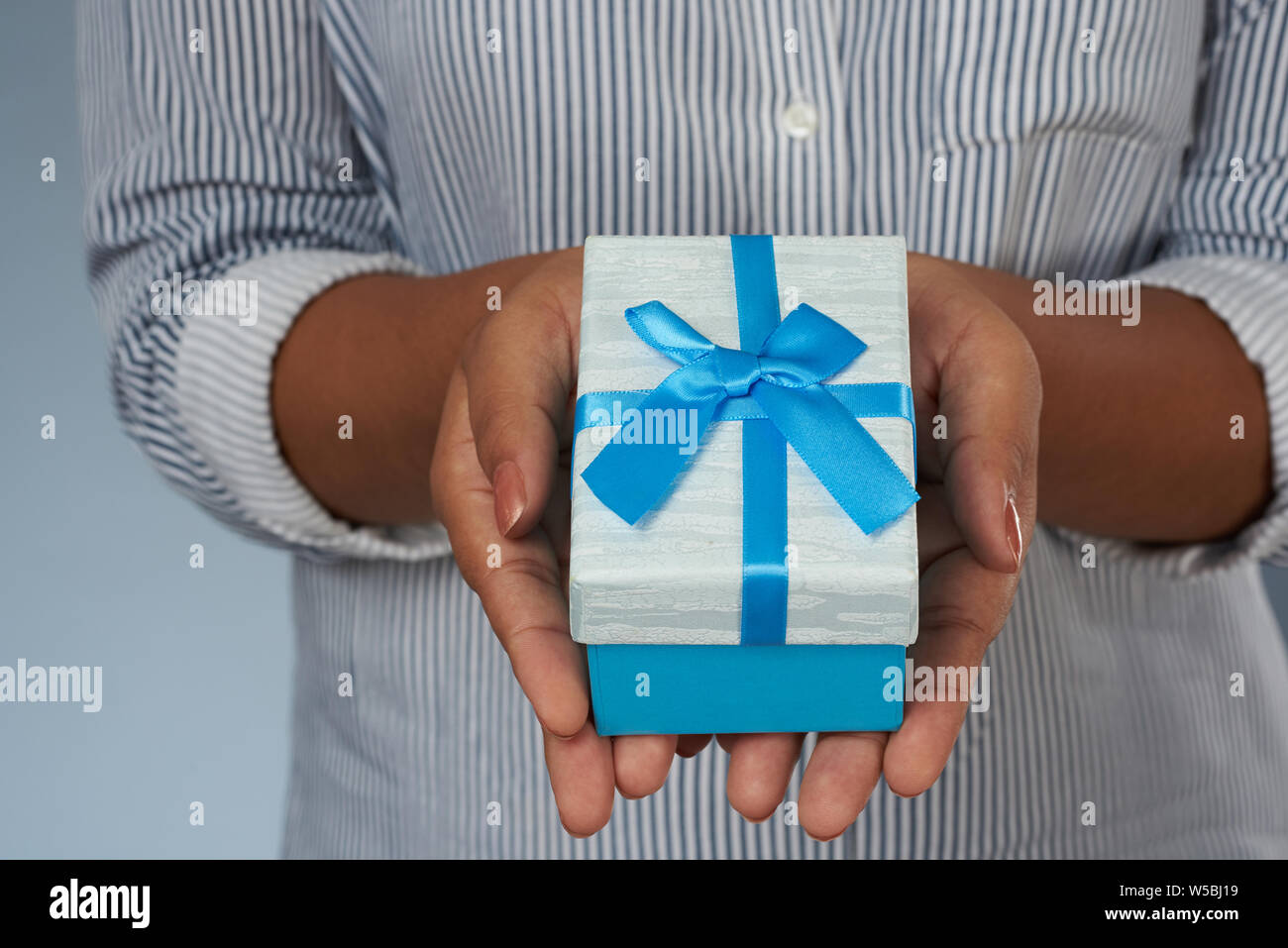 Close up view of blue with ribbon gift box in woman hands Stock Photo