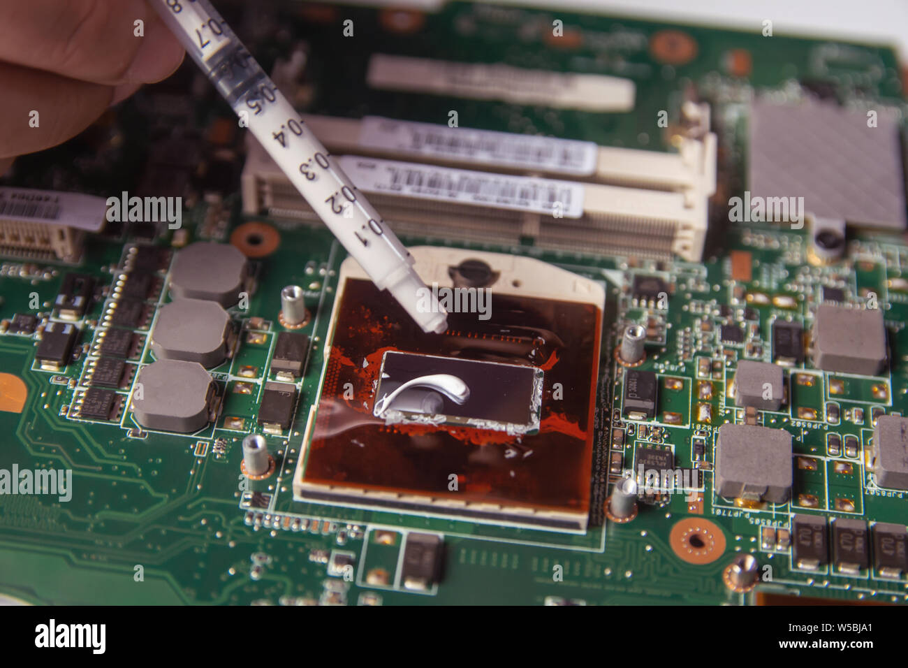 Technician applying thermal paste with syringe on the CPU processor on  motherboard laptop Stock Photo - Alamy