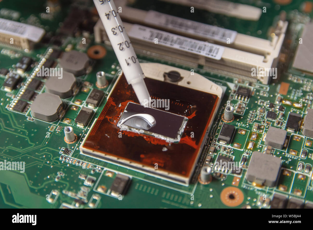 Technician applying thermal paste with syringe on the CPU processor on  motherboard laptop Stock Photo - Alamy