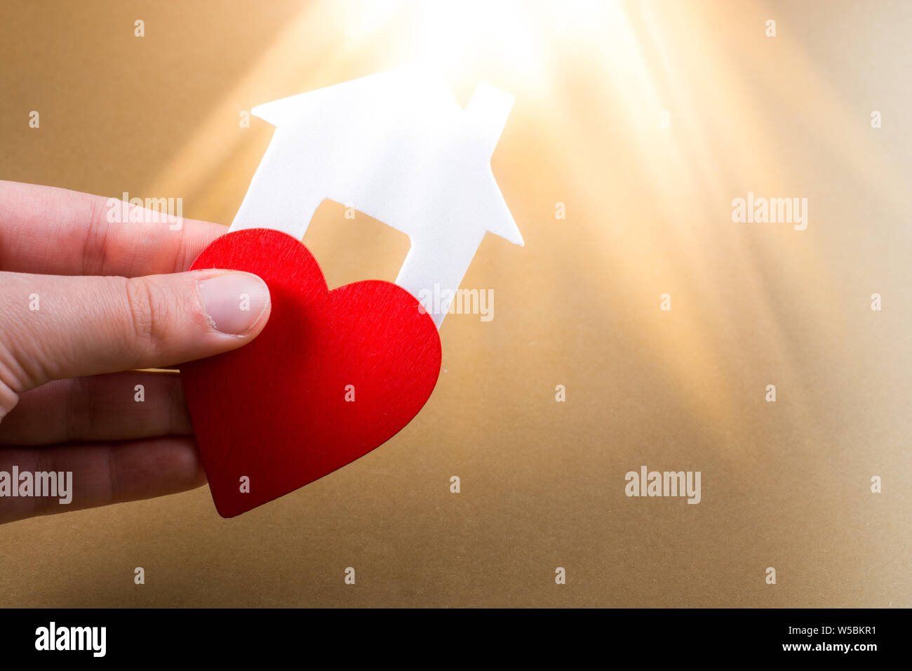 Little house cut out of paper and a heart in hand in view Stock Photo ...