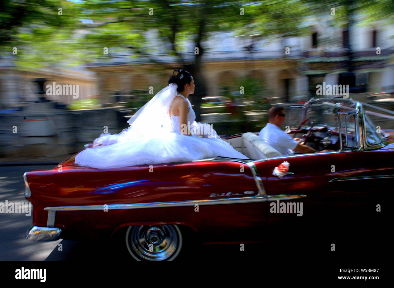 Bride rides along the street of Havana, Cuban in a classic convertible on her wedding day. Stock Photo