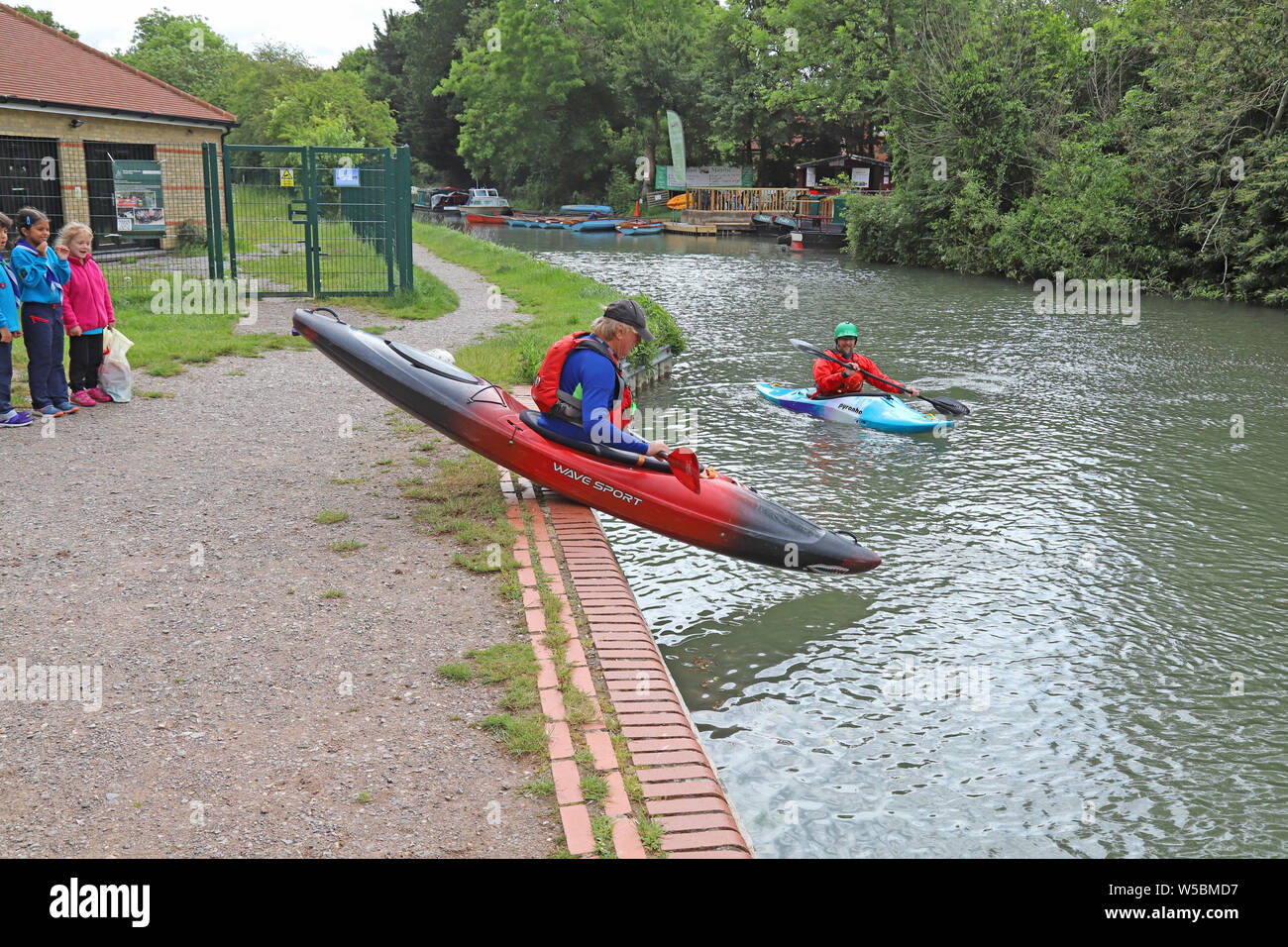 Man scooting his canoe/kayak and tipping into the water from the bank