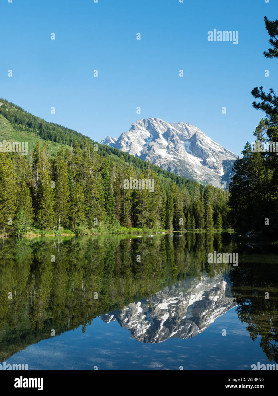 Snow-capped mountains reflected in the calm waters of String Lake, Grand Teton National Park, Wyoming, USA. Stock Photo