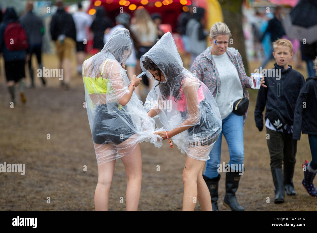 Standon, UK. Saturday 27 July 2019.  A couple of friends adjusting there ponchos at Standon Calling set in the picturesque grounds of Standon Lordship © Jason Richardson / Alamy Live News Stock Photo
