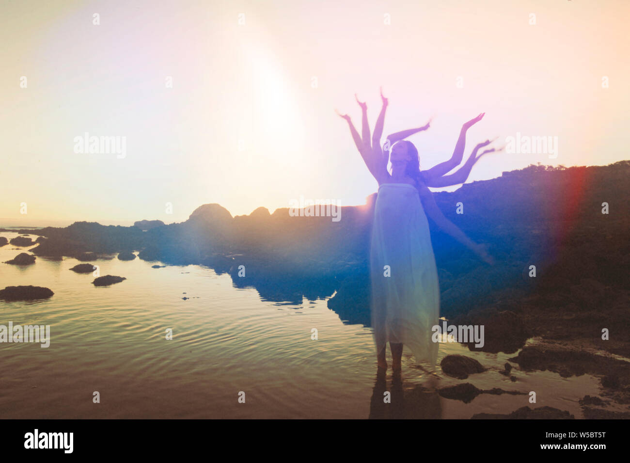 Divine Woman with many arms standing in the sea. Stock Photo