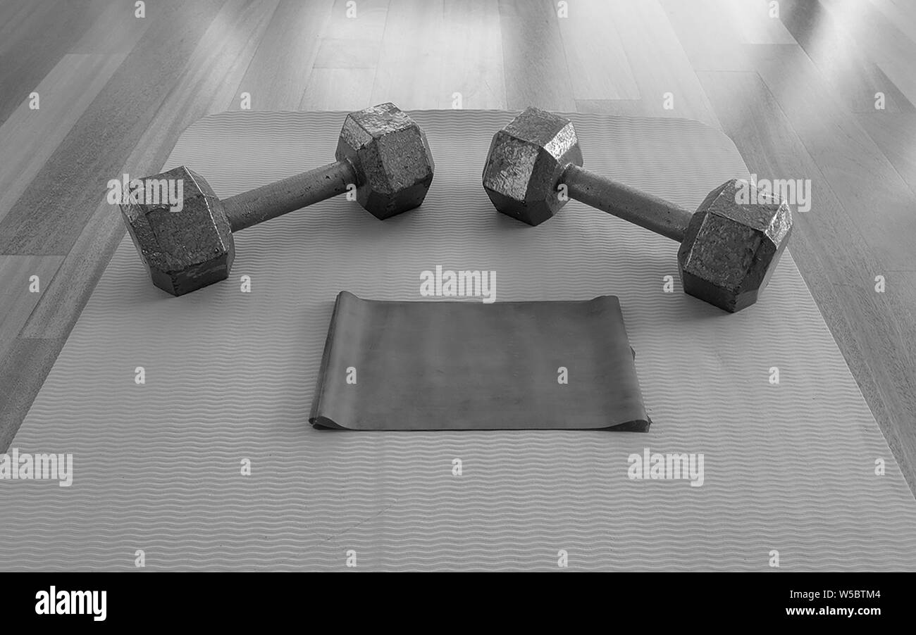 Black and white version of Close up of Dumbbells and Exercise band on a Yoga Mat for a Home workout Stock Photo