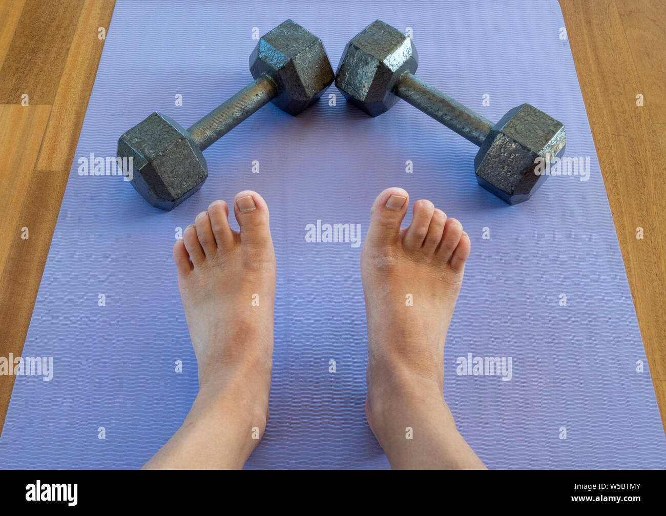 Feet and Dumbbells after a home workout on a yoga mat Stock Photo