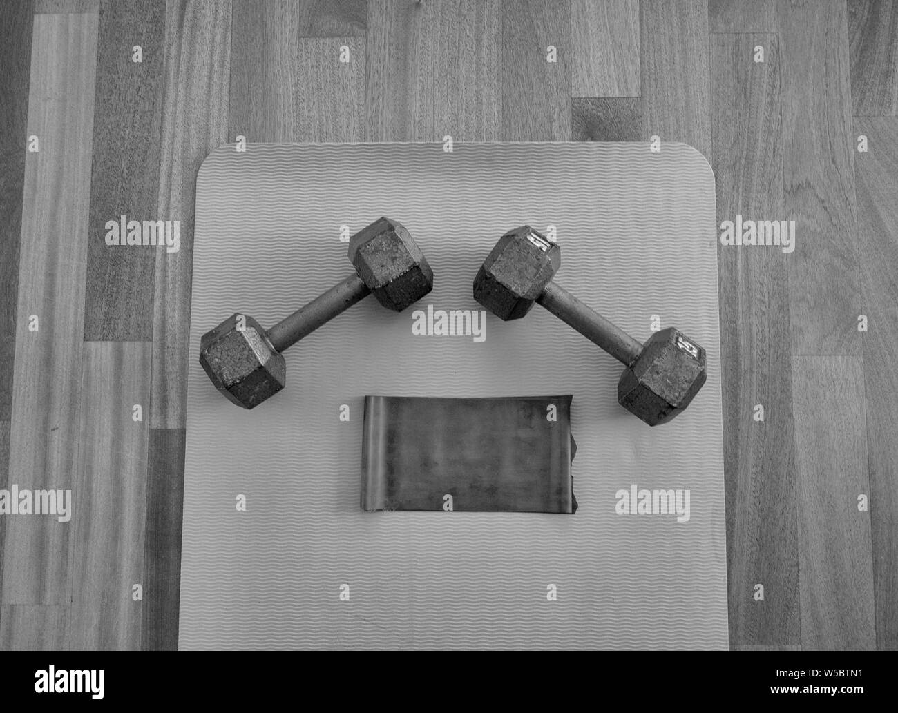 Black and white version of Dumbbells and Exercise band on a Yoga Mat for a Home workout Stock Photo