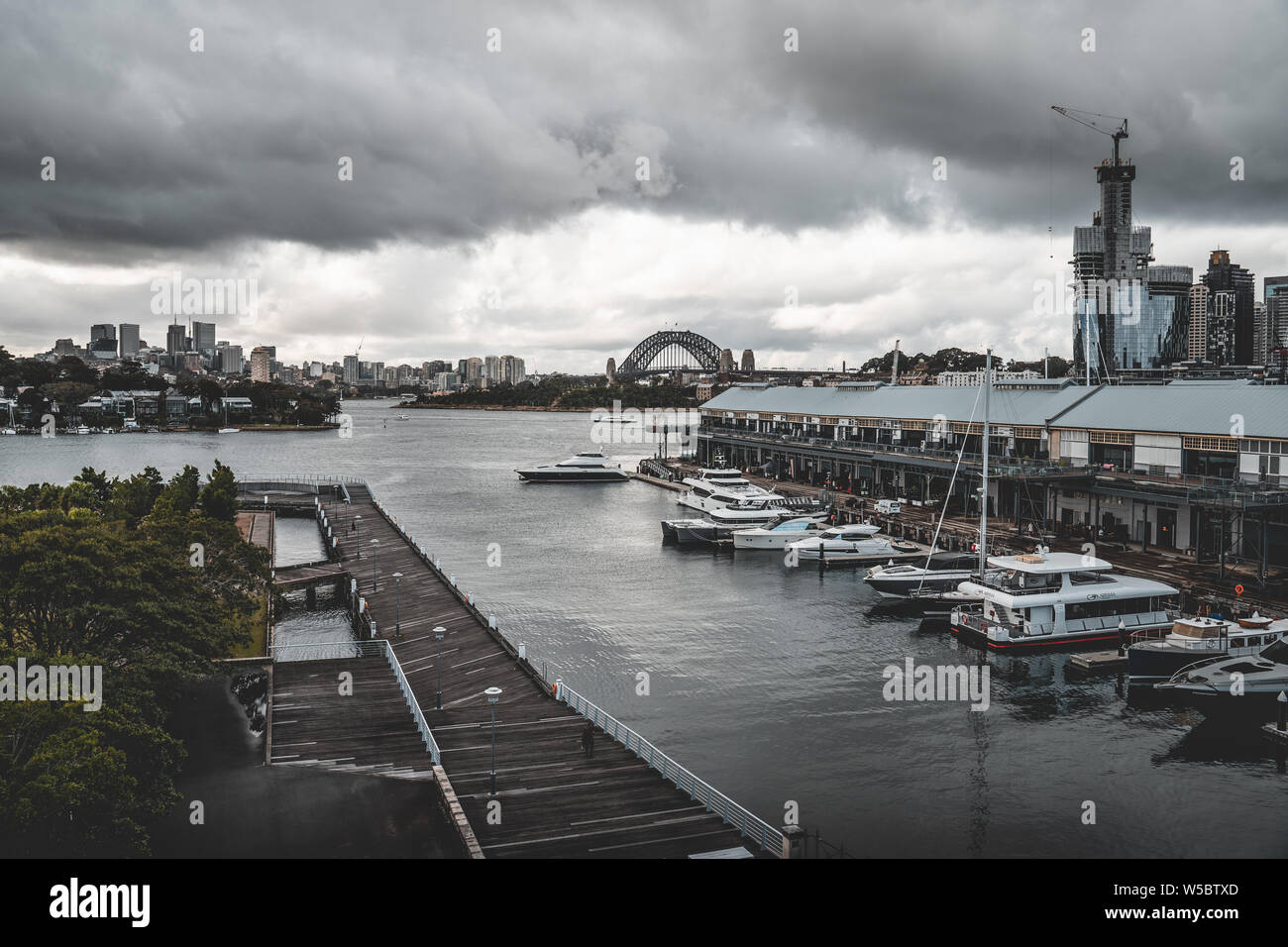 Pyrmont, New South Wales - JUNE 24th, 2019: Ominous clouds hang over Jones Bay Wharf with North Sydney and the Sydney Harbour Bridge visible in the ba Stock Photo