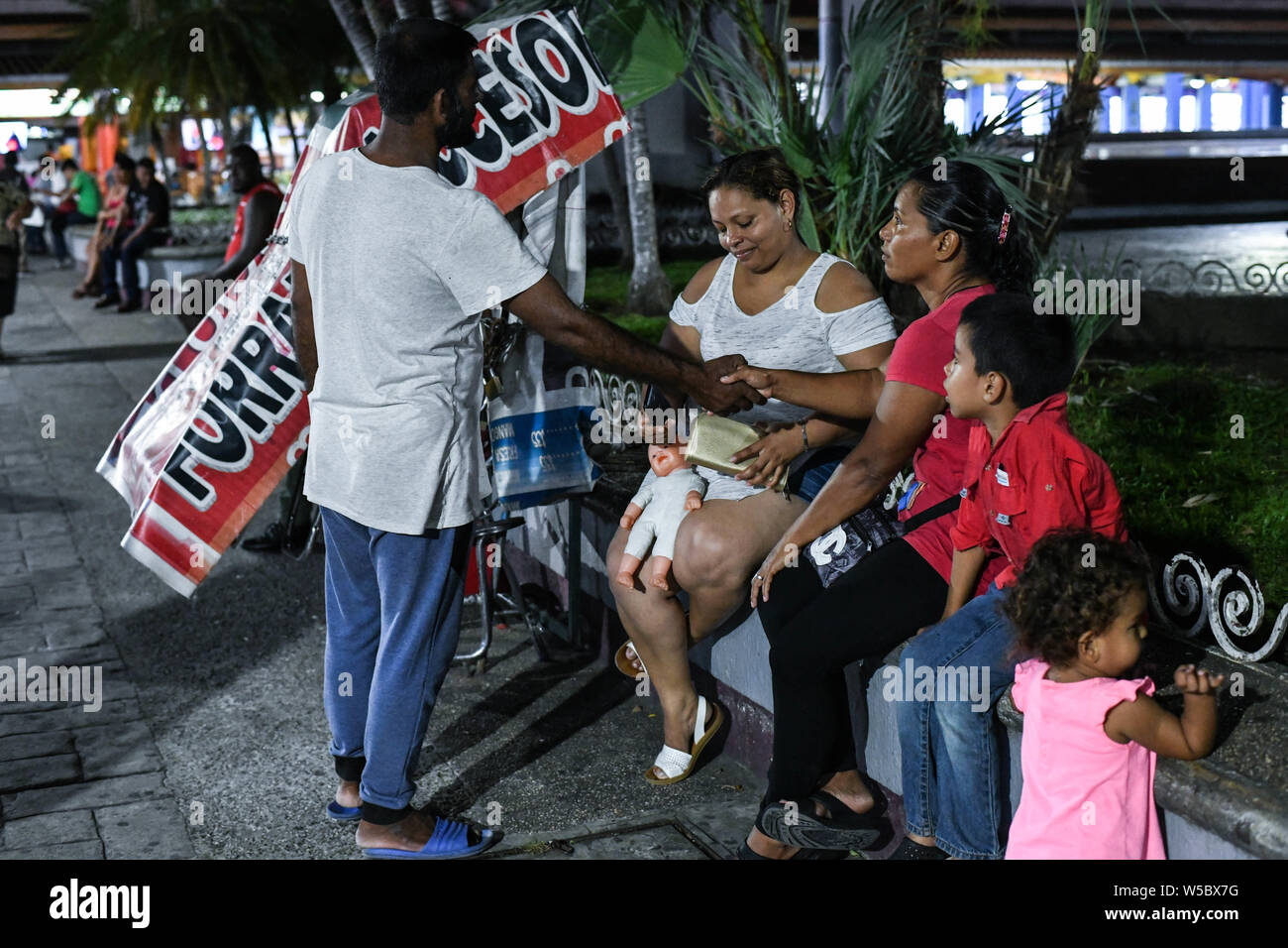 Chiapas, Mexico. 26th July, 2019. The new global melting pot: a Blangadesh migrant, chats with Honduran families at main plaza, founding father Miguel Hidalgo in downtown Tapachula. Mexico has witnessed an increase of migrants crossing the country to reach the US, and now hundreds wander the streets of this southern Mexican city, which is becoming one more new global melting pot. Credit: ZUMA Press, Inc./Alamy Live News Stock Photo
