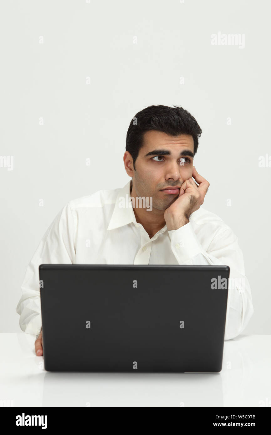Indian businessman working on a laptop and thinking Stock Photo - Alamy