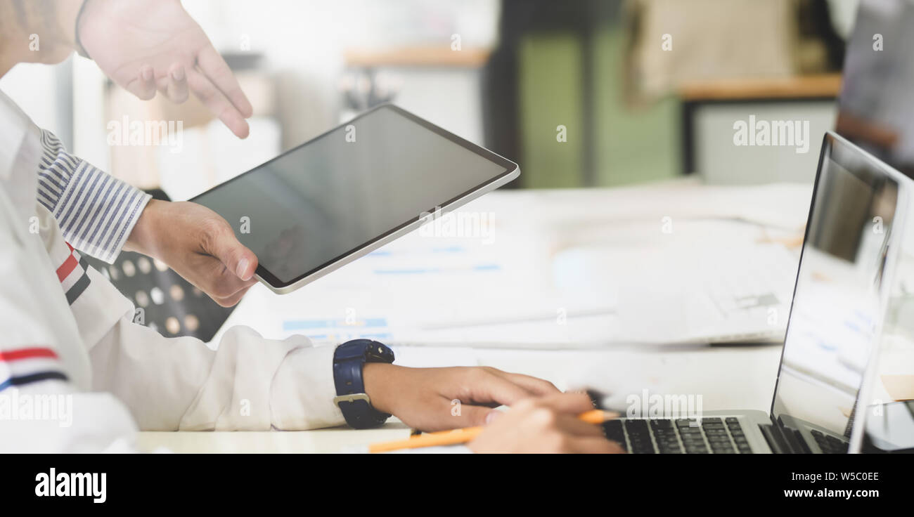 Young successful designers team brainstorming their upcoming project while working on tablet computer Stock Photo