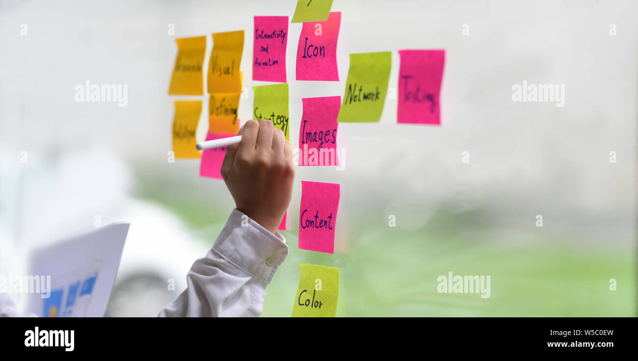 UI UX designer collecting any idea and stick it on the glass window Stock Photo