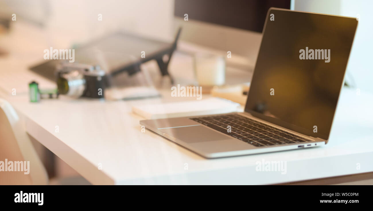 Laptop on modern white table with abstract blurred background Stock Photo