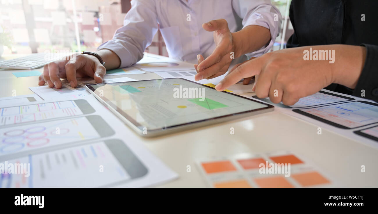 UX Designer team sketch mobile app developer outlines an app on tablet for web mobile smart phone Stock Photo