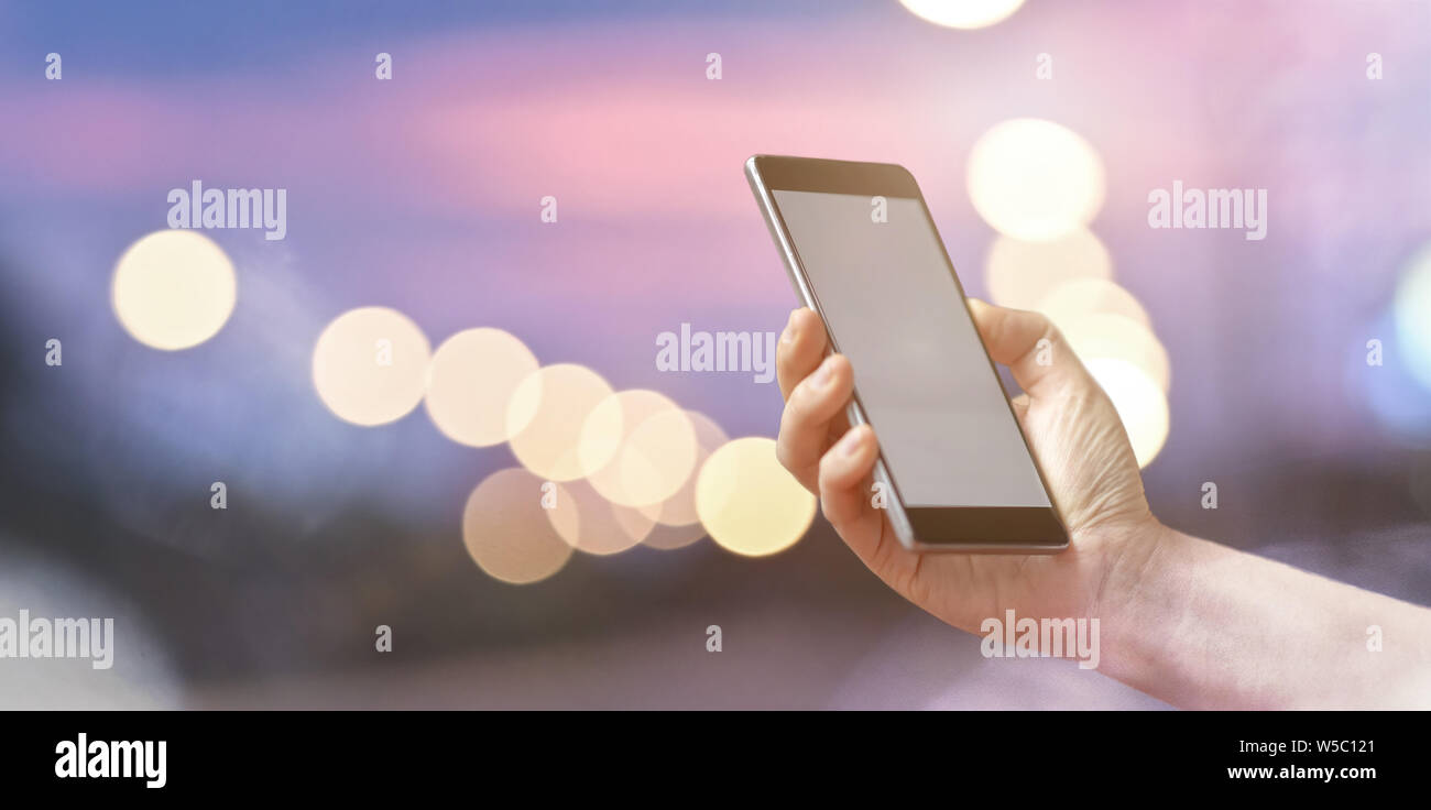 Closeup female hand holding mobile smart phone over light bokeh Stock ...