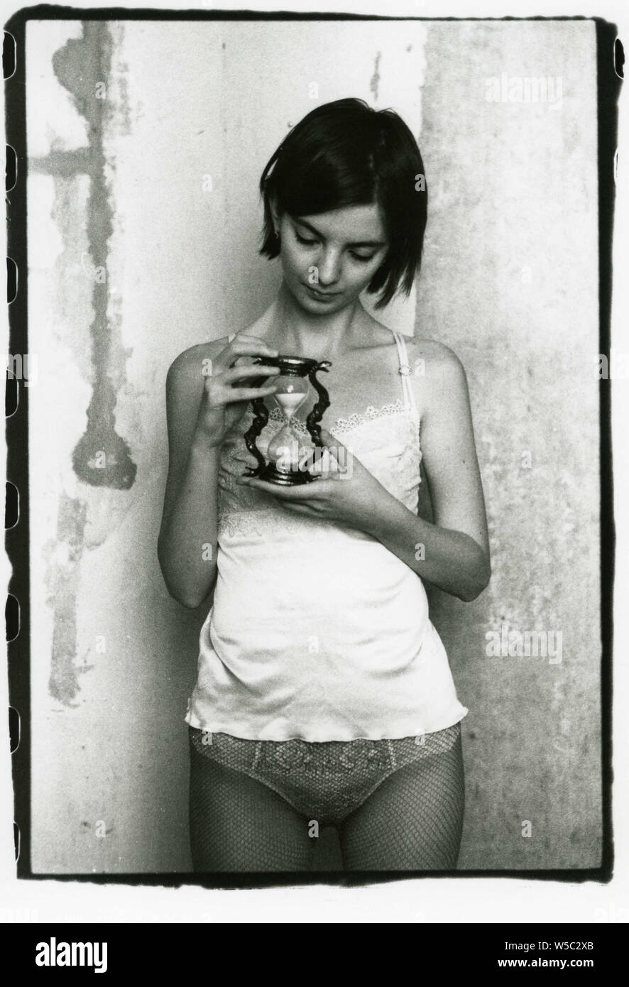 Girl in panties, pantyhose and nightgown holding an hourglass. Attention!  Image contains grit and other analog photography artifacts! Stock Photo -  Alamy
